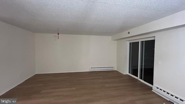 unfurnished room with a baseboard radiator, dark wood-type flooring, and a textured ceiling