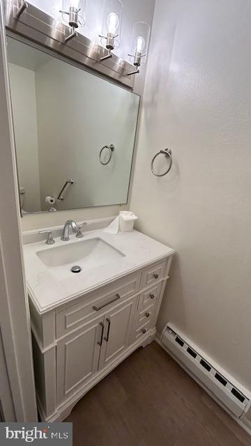 bathroom with hardwood / wood-style flooring, vanity, and a baseboard heating unit