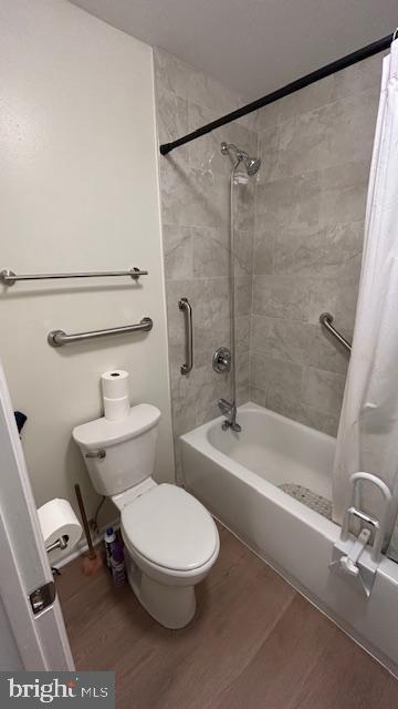 bathroom featuring hardwood / wood-style floors, shower / bath combination with curtain, and toilet