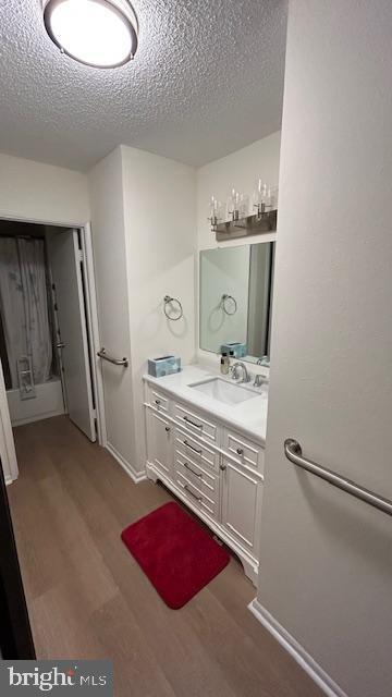 bathroom with hardwood / wood-style flooring, vanity, and a textured ceiling