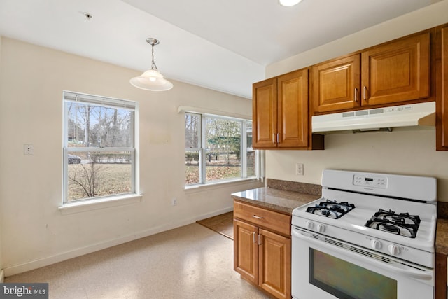 kitchen featuring brown cabinets, decorative light fixtures, under cabinet range hood, and gas range gas stove