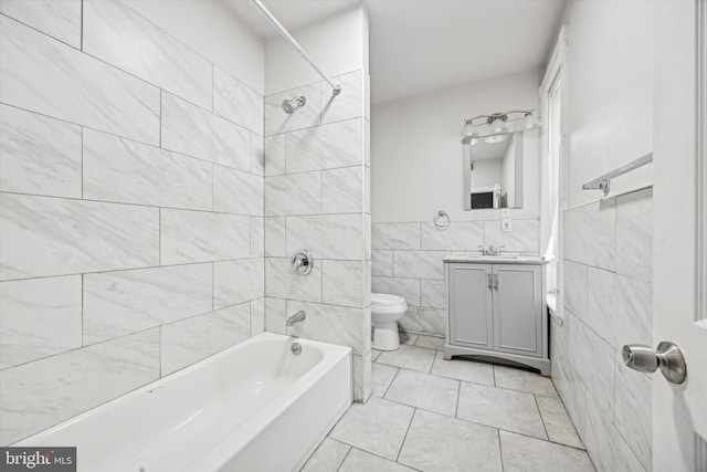 full bathroom with tile walls, tiled shower / bath combo, vanity, tile patterned floors, and toilet