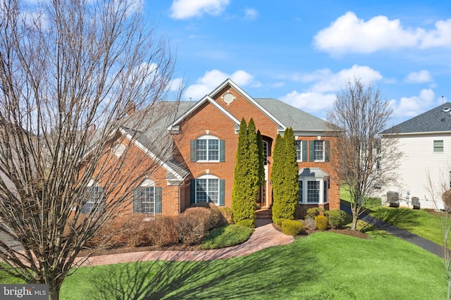 view of front of home with brick siding and a front lawn