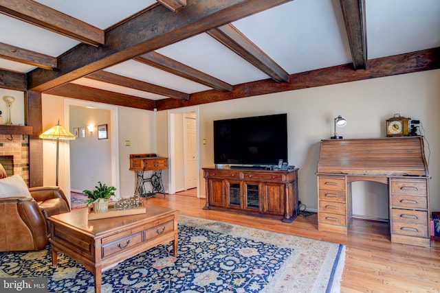 living room featuring a brick fireplace, beamed ceiling, and wood finished floors