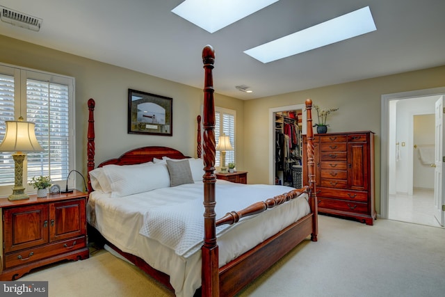 bedroom with light carpet, a skylight, visible vents, a spacious closet, and a closet