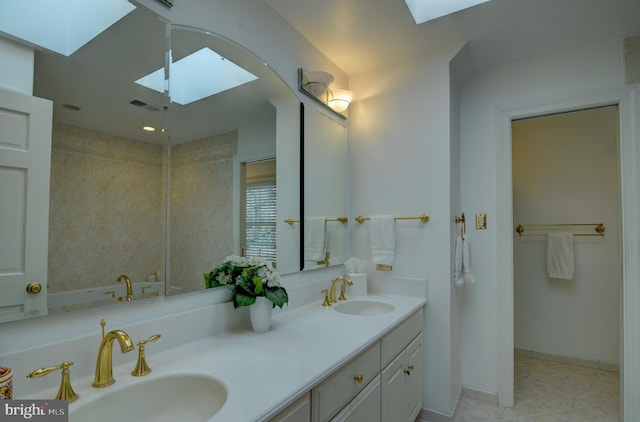 bathroom featuring double vanity, a skylight, visible vents, and a sink