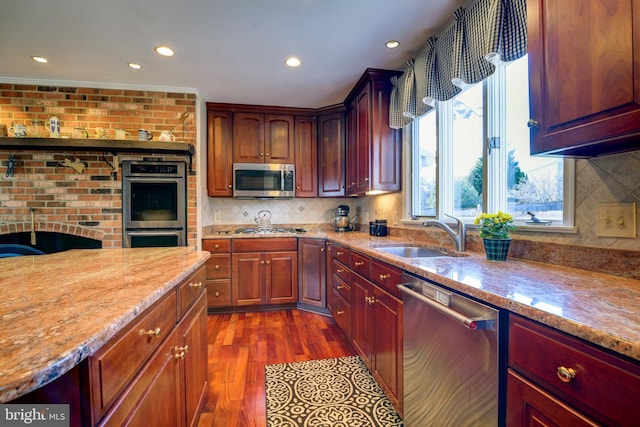 kitchen with dark wood-style floors, appliances with stainless steel finishes, light stone counters, and a sink