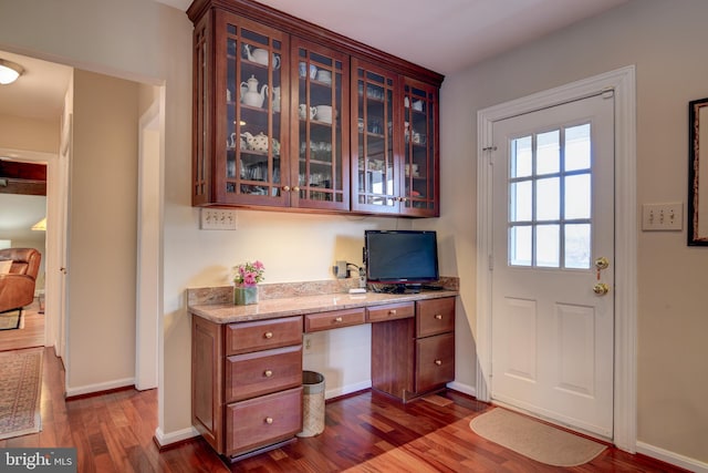 office area featuring dark wood finished floors, built in desk, and baseboards