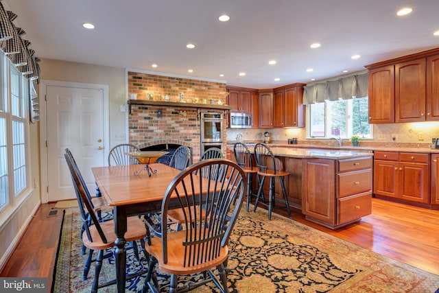 dining space featuring a brick fireplace, light wood-type flooring, visible vents, and recessed lighting