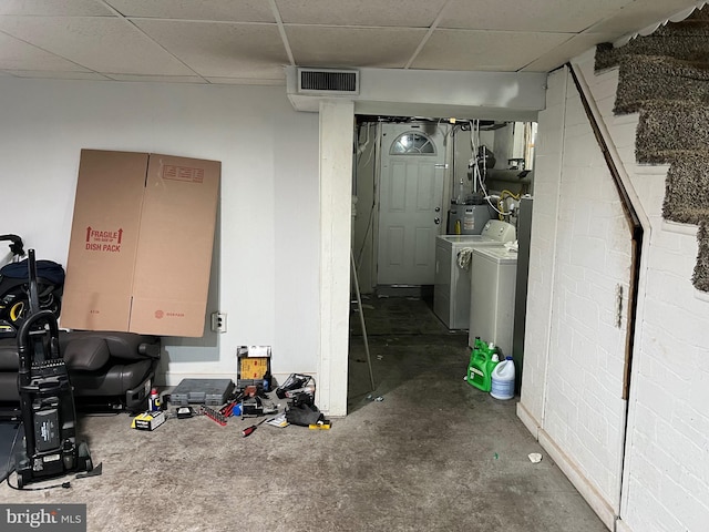 basement featuring water heater, separate washer and dryer, and a drop ceiling