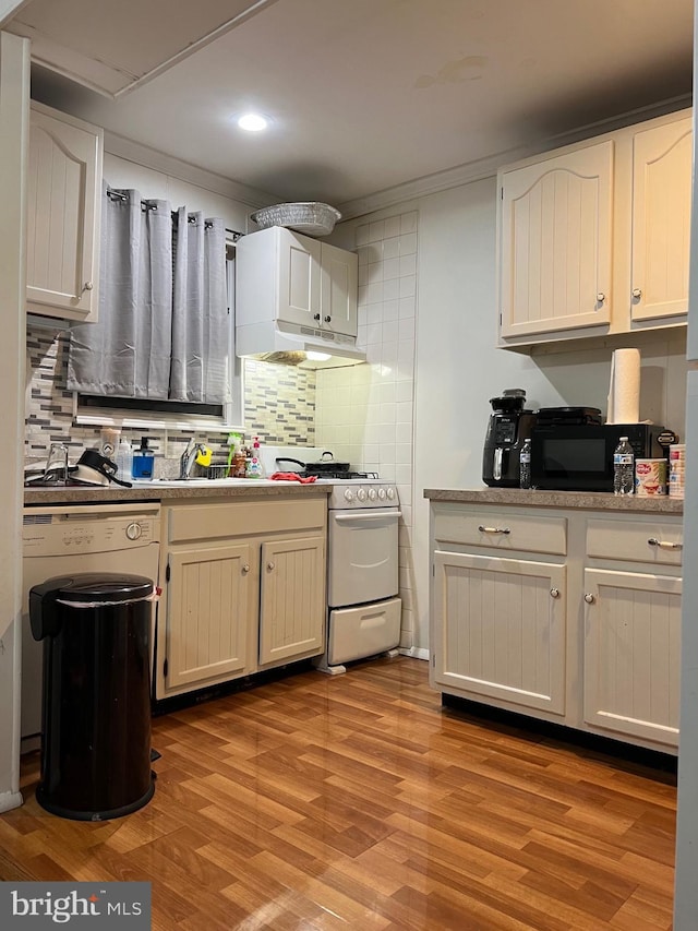 kitchen with sink, gas range gas stove, white cabinetry, light hardwood / wood-style floors, and decorative backsplash