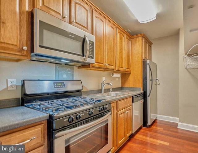 5340 Holmes Run Pkwy Unit 101, Alexandria, VA 22304 - kitchen with appliances with stainless steel finishes, wood finished floors, a sink, baseboards, and brown cabinets