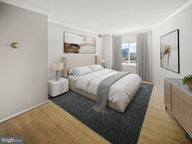 bedroom featuring light wood finished floors, baseboards, ornamental molding, and a textured ceiling