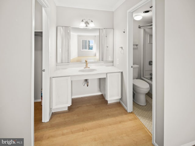 bathroom featuring bathing tub / shower combination, toilet, ornamental molding, vanity, and wood finished floors