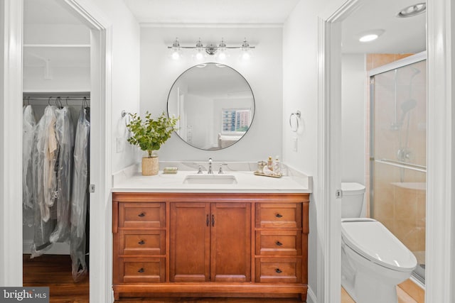 full bath with a stall shower, a walk in closet, vanity, and toilet