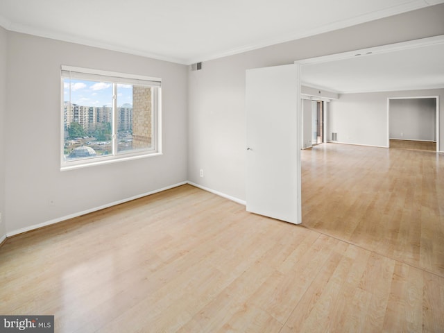 empty room with light wood-style floors, baseboards, visible vents, and crown molding