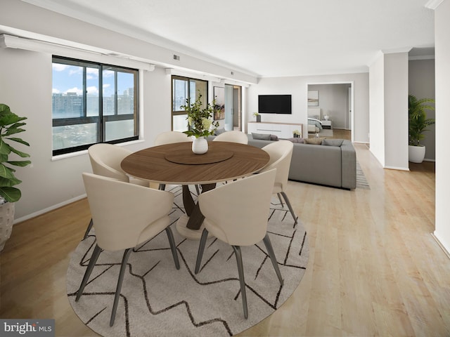 dining area featuring light wood-style flooring, baseboards, and crown molding