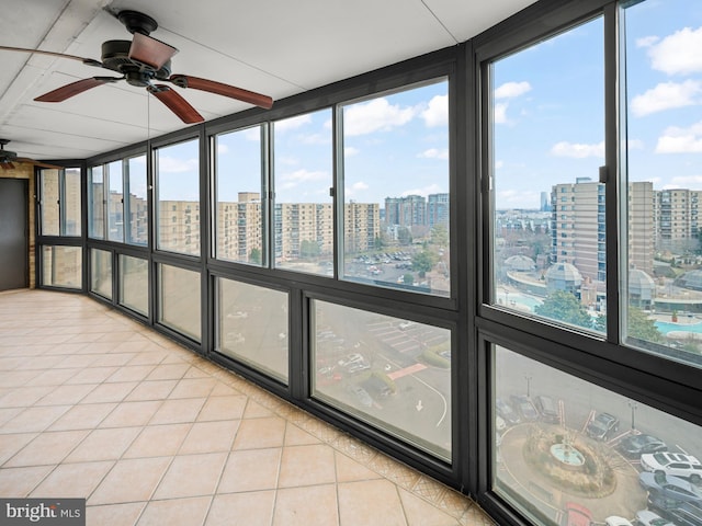 unfurnished sunroom featuring a view of city and a ceiling fan