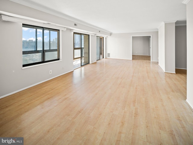 unfurnished room with light wood-style floors, visible vents, baseboards, and crown molding