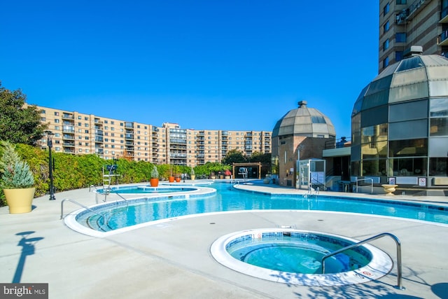 community pool with a patio, a city view, and a hot tub