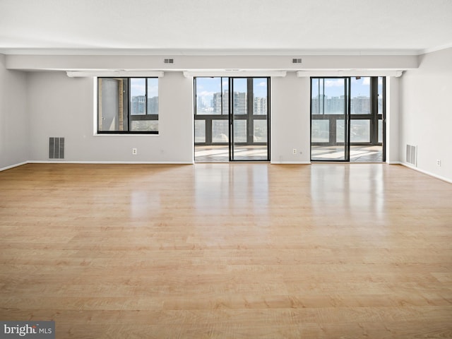 empty room with baseboards, visible vents, and light wood finished floors