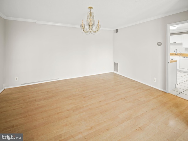 spare room featuring light wood-style floors, visible vents, ornamental molding, and a notable chandelier