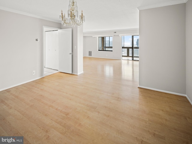 unfurnished dining area with ornamental molding, a chandelier, baseboards, and wood finished floors