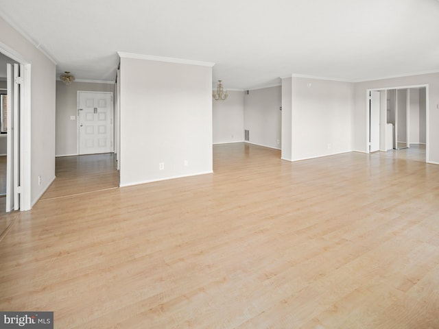 empty room featuring crown molding, light wood-type flooring, baseboards, and an inviting chandelier