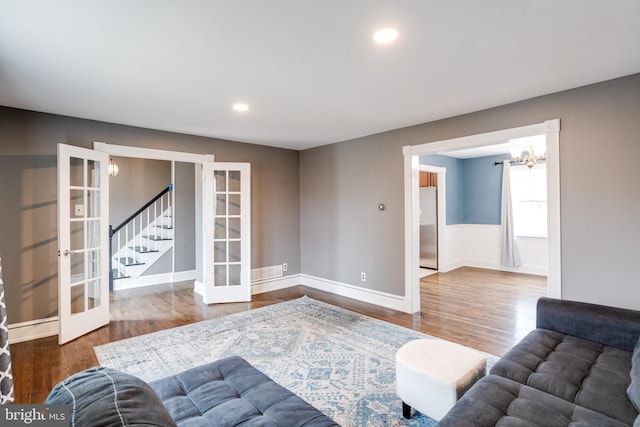 living room with hardwood / wood-style floors, an inviting chandelier, and french doors