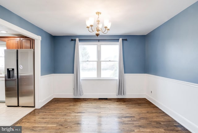 unfurnished dining area featuring a chandelier and light hardwood / wood-style flooring