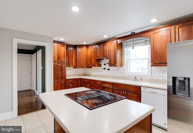 kitchen with sink, light tile patterned floors, stainless steel fridge, dishwasher, and black electric cooktop