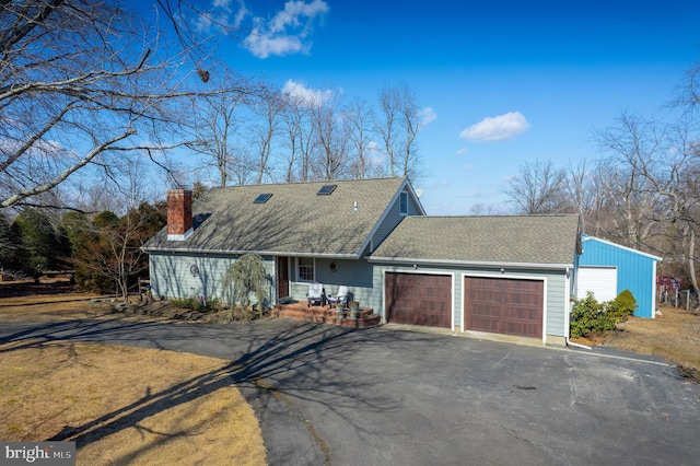 view of front of home featuring a garage, roof with shingles, driveway, and a chimney