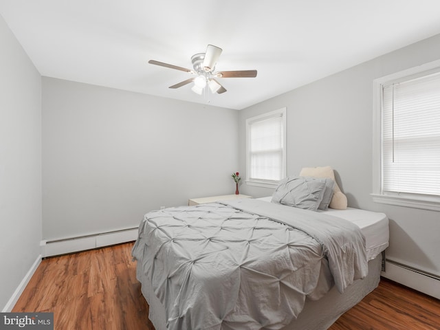 bedroom featuring dark hardwood / wood-style flooring, a baseboard heating unit, and ceiling fan