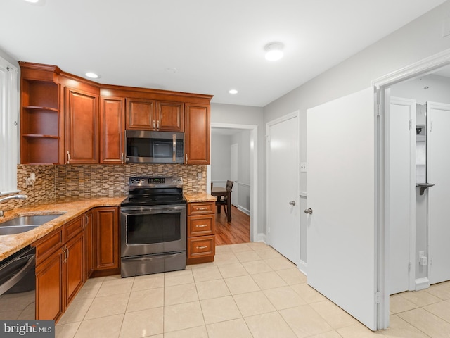 kitchen with sink, backsplash, light tile patterned floors, and appliances with stainless steel finishes