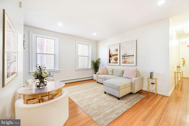 living area with recessed lighting, a baseboard heating unit, baseboards, and light wood-style flooring