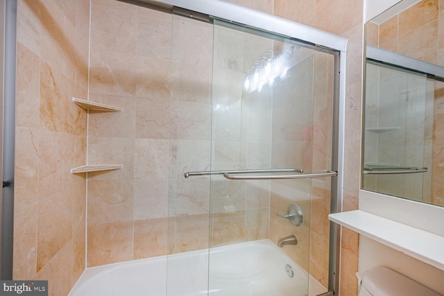 bathroom with toilet and shower / bath combination with glass door