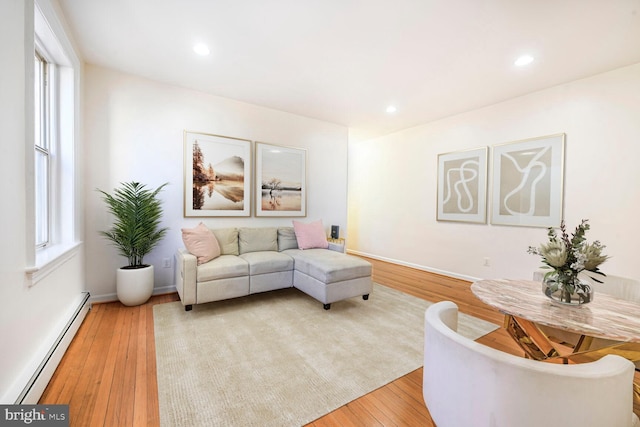 living room featuring recessed lighting, a baseboard heating unit, baseboards, and light wood finished floors