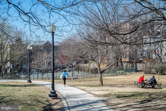 view of home's community with a residential view, a lawn, community basketball court, and fence