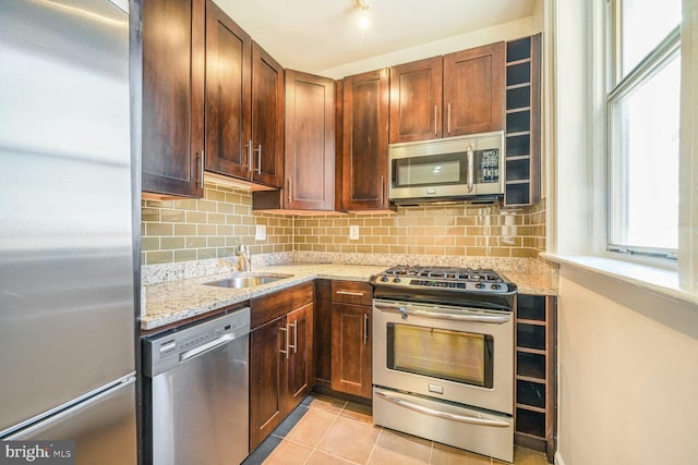 kitchen with a sink, decorative backsplash, light tile patterned floors, and stainless steel appliances