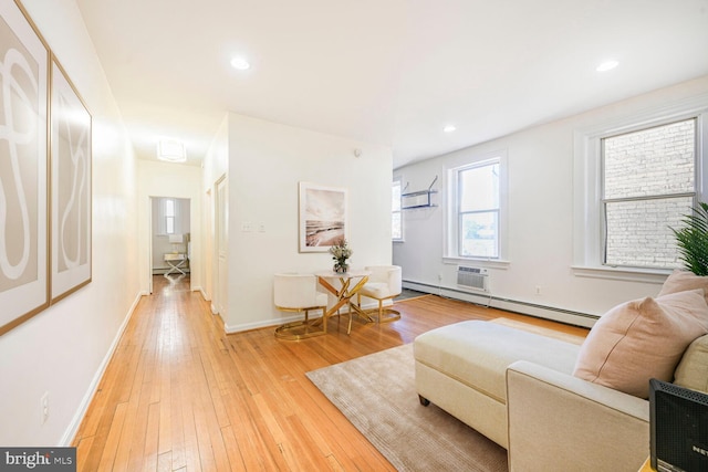 living area featuring baseboard heating, recessed lighting, light wood-type flooring, and baseboards