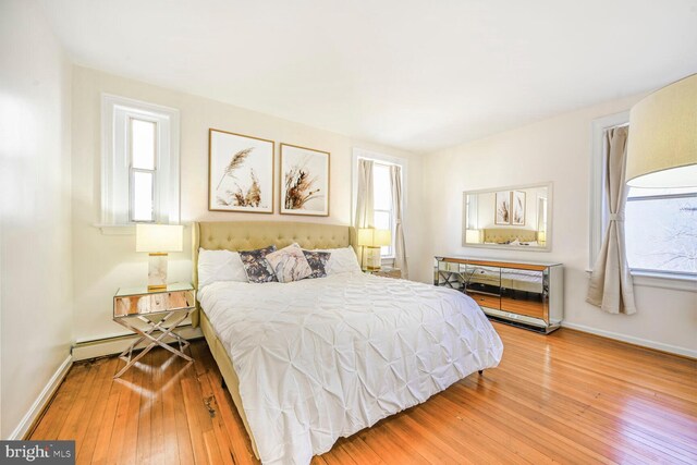 bedroom featuring baseboards, multiple windows, and hardwood / wood-style floors