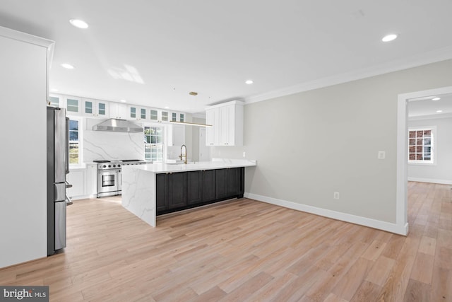 kitchen featuring appliances with stainless steel finishes, white cabinets, a sink, a peninsula, and under cabinet range hood