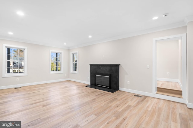 unfurnished living room featuring crown molding, a fireplace, visible vents, and light wood-style floors