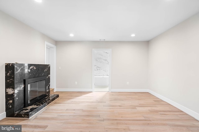 unfurnished living room with light wood finished floors, a fireplace, baseboards, and recessed lighting