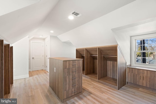 additional living space featuring baseboards, visible vents, vaulted ceiling, light wood-style floors, and recessed lighting