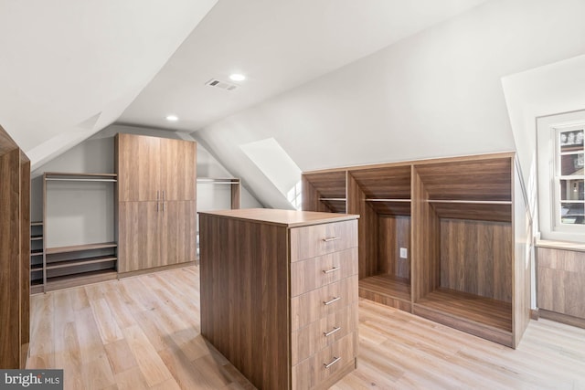 spacious closet featuring lofted ceiling, light wood finished floors, and visible vents