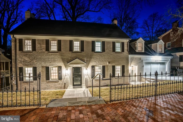 view of front of property with driveway, a fenced front yard, a chimney, and brick siding