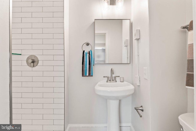 bathroom with toilet, sink, and a tile shower