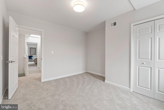 unfurnished bedroom with light carpet and a closet