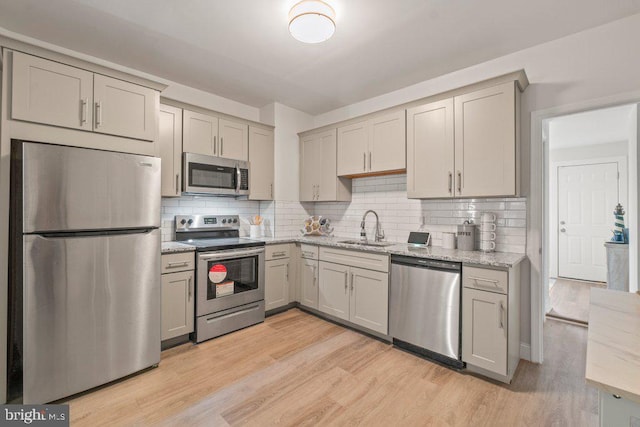 kitchen featuring tasteful backsplash, sink, light hardwood / wood-style floors, and appliances with stainless steel finishes